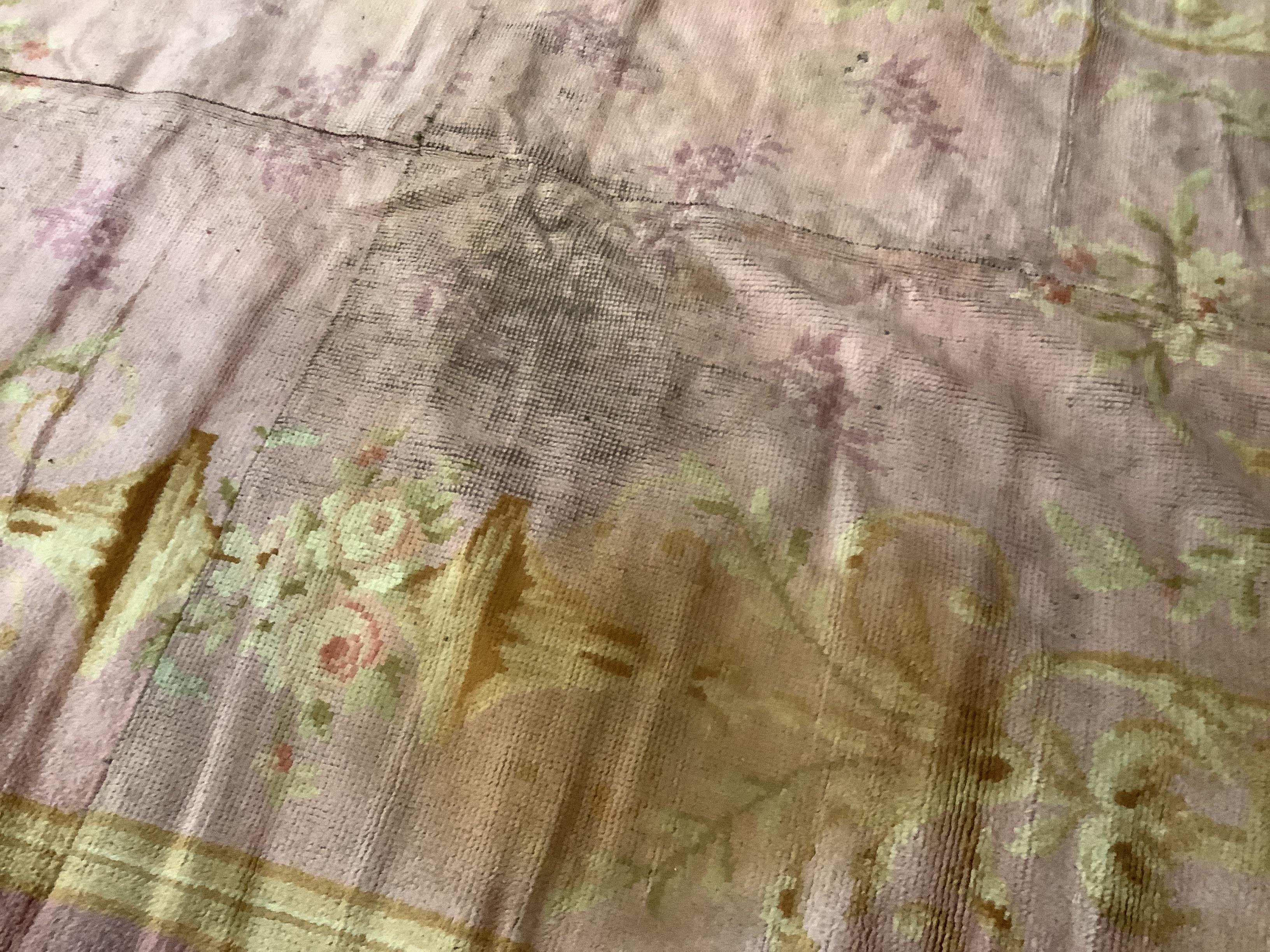 An antique Donegal carpet, with scrolling motifs on a pale, pink ground, cut and reduced in size, 386 x 210cm